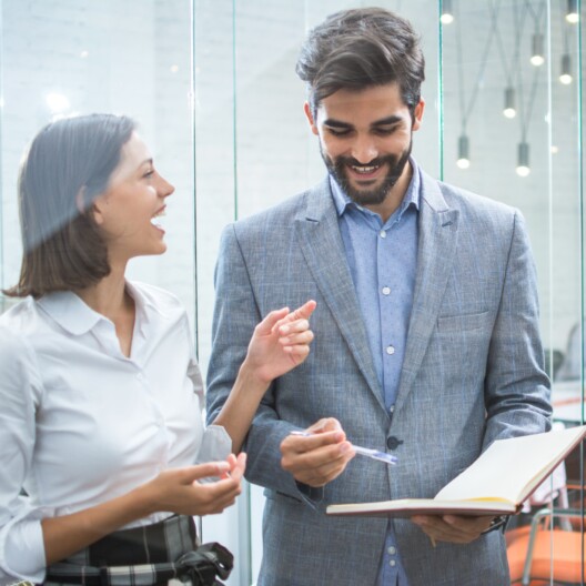 Business team discussing business documents, standing in the office lobby.